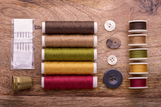 cotton sewing autumn color with buttons, needles and thimble on wood