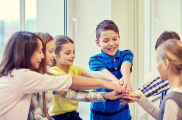 group of smiling school kids putting hands on top - Powered by Adobe