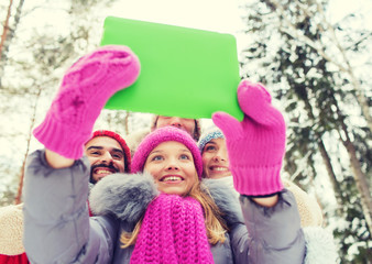 smiling friends with tablet pc in winter forest