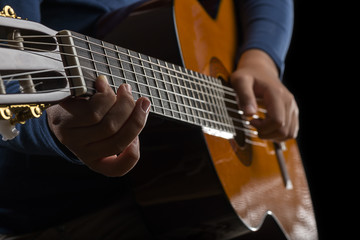 Close-up of child playing classical guitar. 
