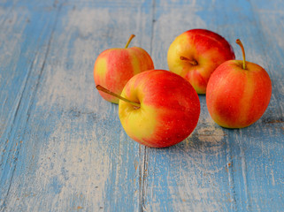 Four red apples  on blue wooden floor.