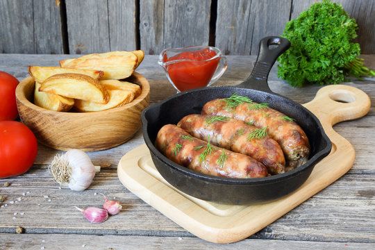 Grilled meat sausages and potatoes in a pan
