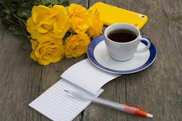 still life bouquet of yellow roses, coffee and notebook