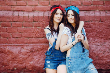 twins girls hugging front of the urban wall background.