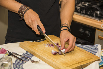 Man Chopping Red Onion with Sharp Knife in Kitchen