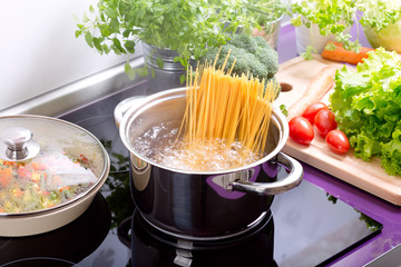 pan of boiling water with spaghetti on the cooker - obrazy, fototapety, plakaty