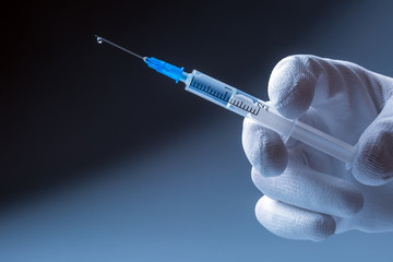 Medical syringe with needle in hand doctor. At the end of the needle drop of liquid