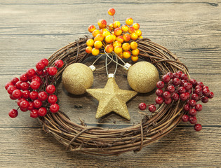 Glittering gold Christmas balls, bells,wreath, and star on wooden background with snow .