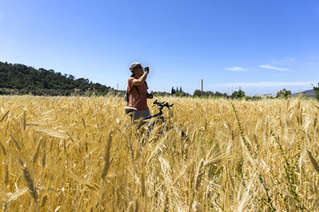 Cyclist man is drinking water on hay bale in a field