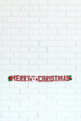 Fototapeta na wymiar Merry Christmas sign hanging on white brick wall as decoration