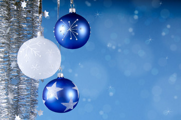 Weihnachtskugeln mit Lametta vor blau