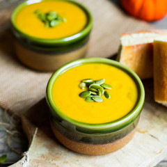 Creamy pumpkin soup with seeds on wooden background