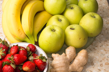 Still life of bananas, apples, strawberries and ginger.