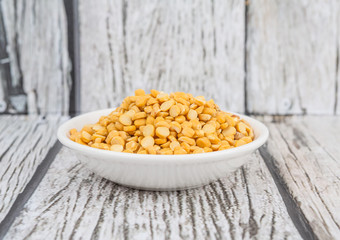 Raw Indian dhal in white bowl over wooden background