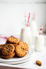 Oatmeal cookies with milk in jars on white wooden background