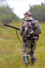 hunter in camouflage shooting on the forest edge