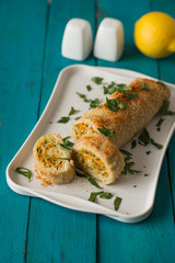 Fish roll with greens and carrots on the cyan table vertical