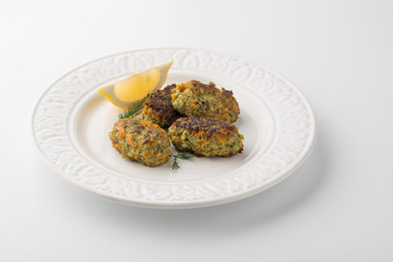 Rissoles with vegetables and greens on the white plate with slice of lemon