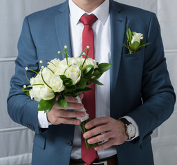 a bouquet of roses in hands of the groom