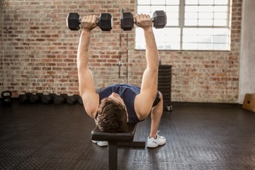 Man lifting dumbbells while lying on exercise bench