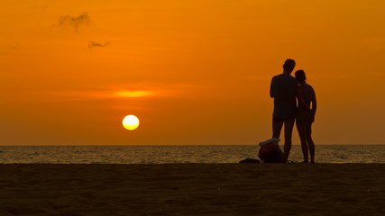 Loving couple enjoying sunset on a sandy beach