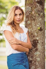 Fototapeta premium Beautiful woman with arms crossed standing by tree 