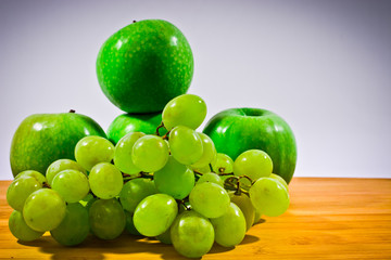 four green apples and grapes on white background