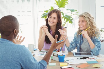 Happy business people discussing while working at desk 