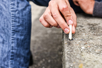 Hand of a young man extinguish cigarette on a stair