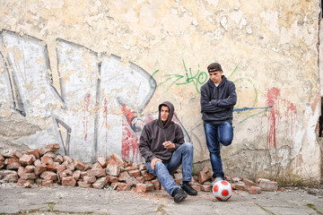 two street hooligans or rappers standing against a graffiti pain