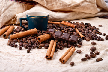 Cup of hot coffee with cinnamon sticks, bitten bar of chocolate