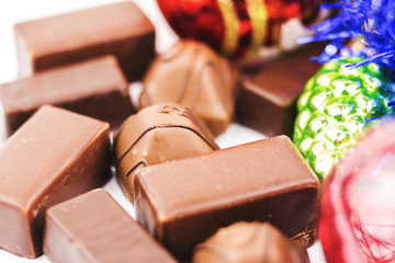 Close-up delicious chocolate candy and Christmas decorations on white background
