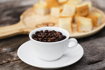 Coffee beans in cup  on wood background with Toast and butter milk