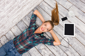 Top view of young woman lying on the floor with tablet and phone