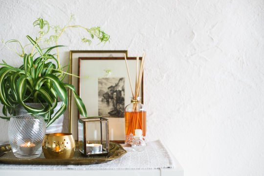 Vintage home decor: candles, aroma diffuser, plant and frames. Selective focus
