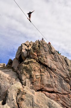 Un &eacute;quilibriste marche sur un c&acirc;ble tendu entre deux rochers &agrave; Plougrescant en Bretagne