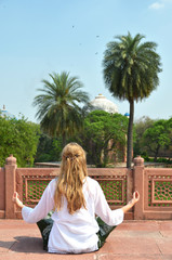 Fototapeta na wymiar Young woman meditating in the yard of Humayun's Tomb. Delhi, Ind