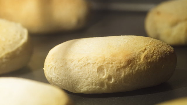 Time lapse zoom-in of biscuits baking on a cookie sheet in an oven; shallow focus on one biscuit.