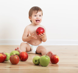 Fototapeta premium Portrait of a cute little child with apples indoor