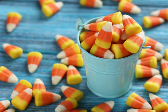 Halloween candy corns in bucket on blue wooden background - Powered by Adobe