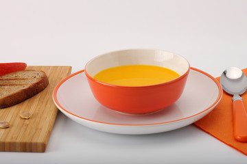 bowl of pumpkin hokkaido soup with bread  on white