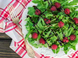 arugula salad with raspberries and balsamic vinegar in a white p