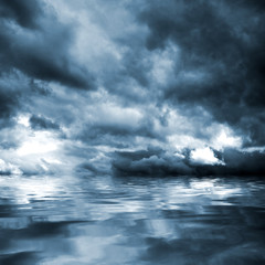 Dark storm clouds before rain above the water level. Natural background.