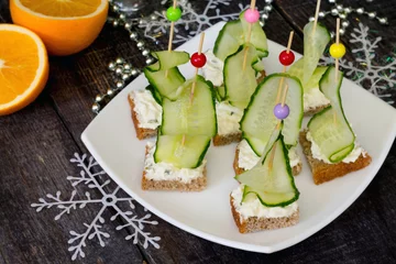 Tuinposter Appetizer canape sandwich with a cucumber on a wooden table © elena_hramowa