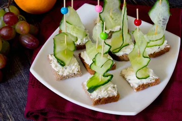 Gordijnen Appetizer canape sandwich with a cucumber on a wooden table © elena_hramowa