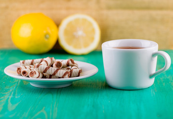 Tubules wafer and tea with a lemon on an old table