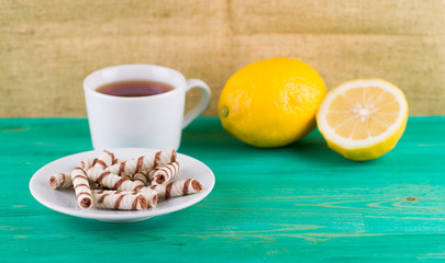Tubules wafer and tea with a lemon on an old table
