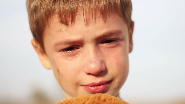 dirty orphan boy close-up crying and looking at camera on the
