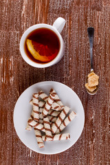 Tubules wafer and tea with a lemon on an old table