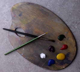 wooden art palette with colors and two brushes